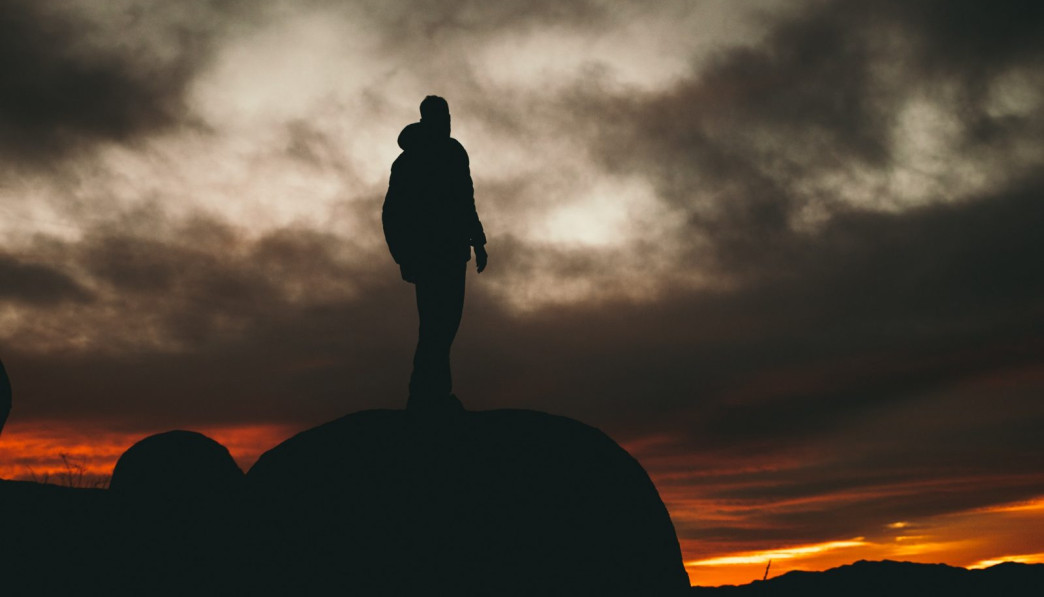 man standing on rock during golden hour
