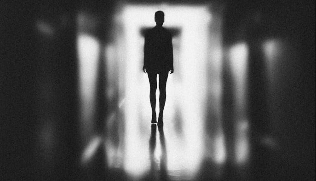Monochrome Photo of Person Standing on Hallway