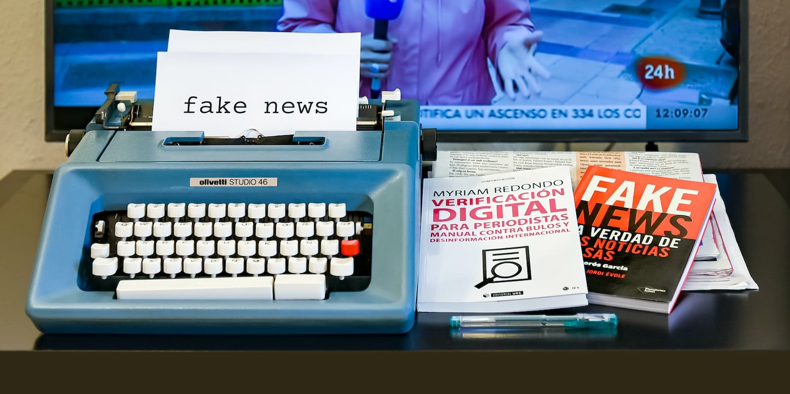 een typemachine met daarop fake news en boeken over fake news