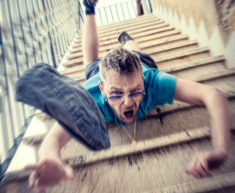 man in blue t-shirt and blue denim shorts sitting on concrete stairs during daytime