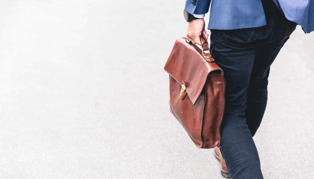 person walking holding brown leather bag