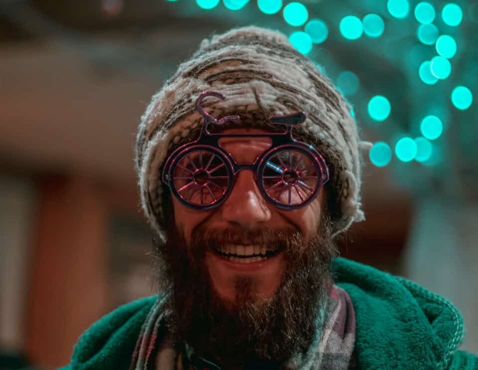 selective focus photography of man wearing gray knit cap, red-and-gray scarf and green cable knit zip hoodie