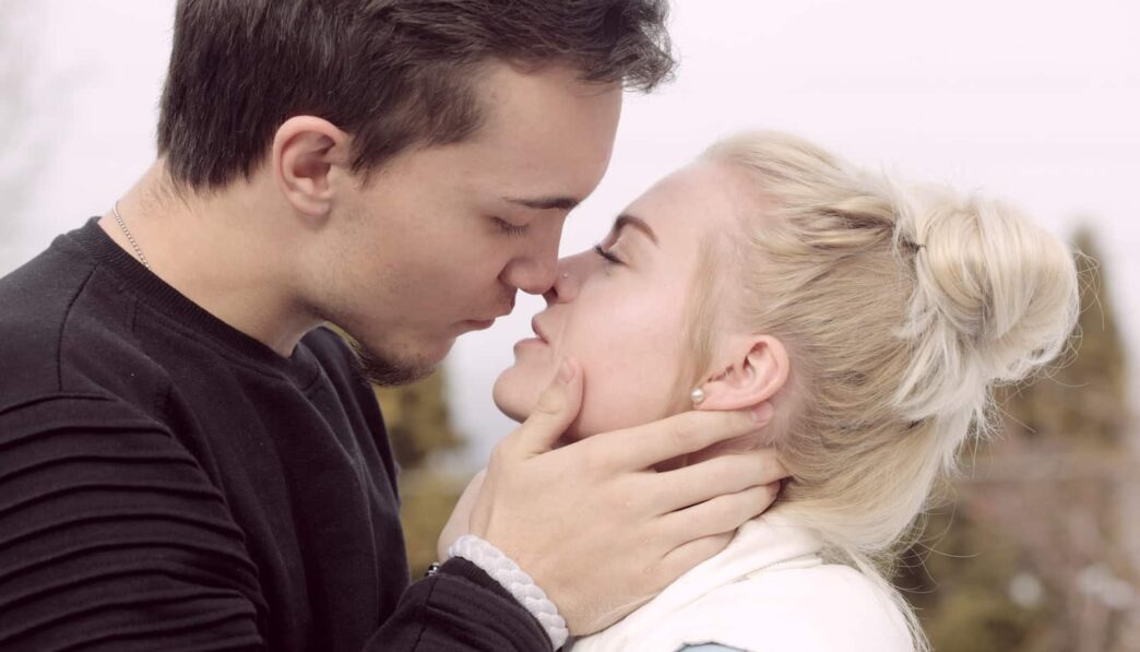 man wearing black top about to kiss woman
