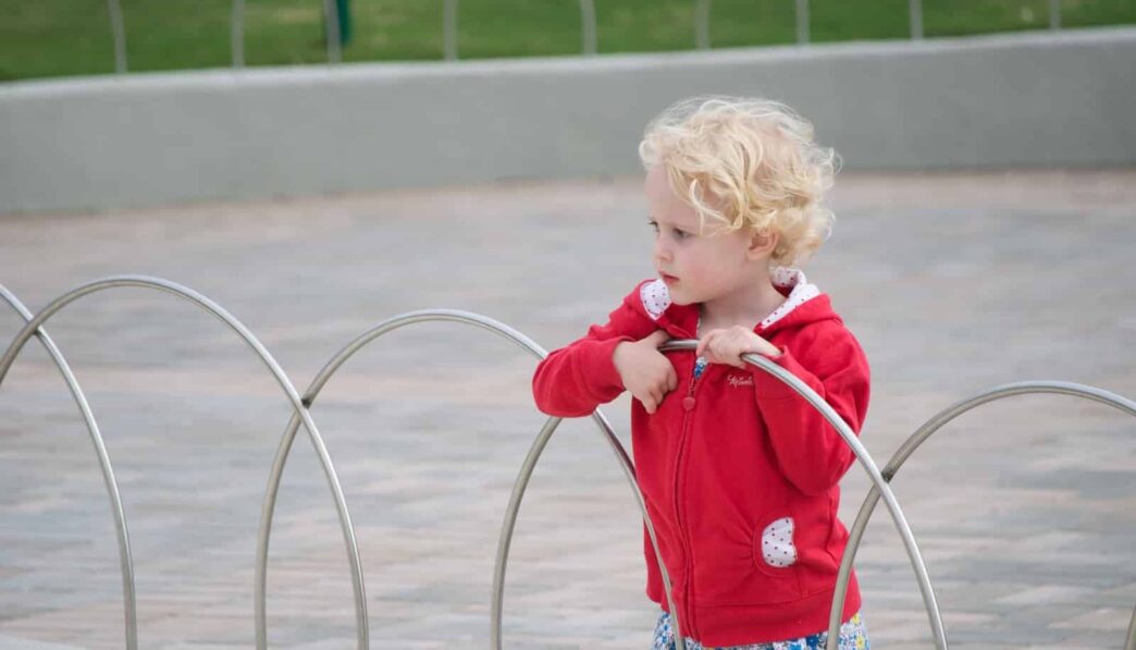 girl in red long sleeve shirt holding red hose
