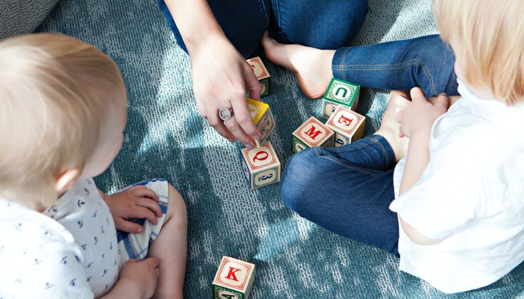 two toddler playing letter cubes