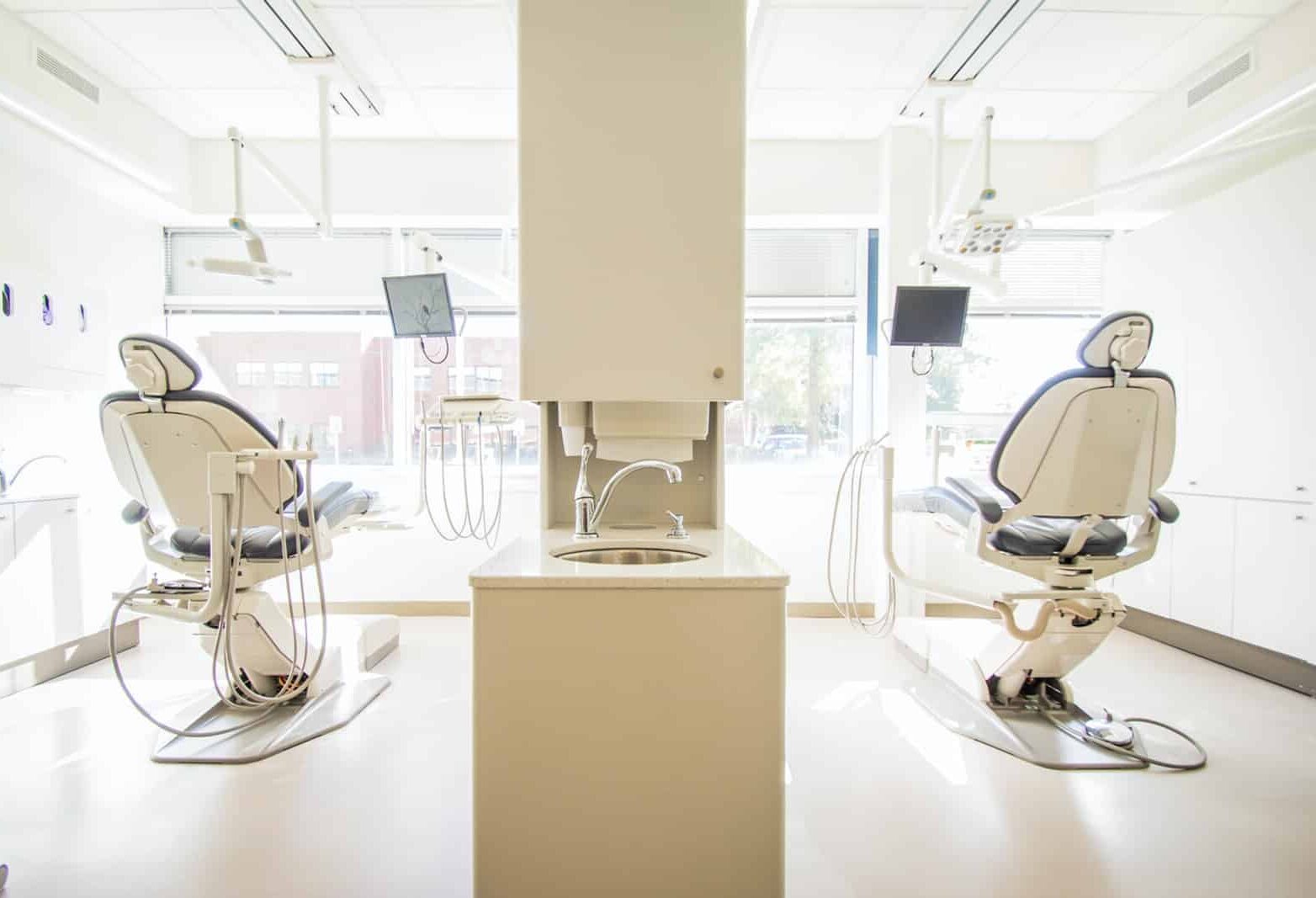 two white dentist chairs inside white painted room