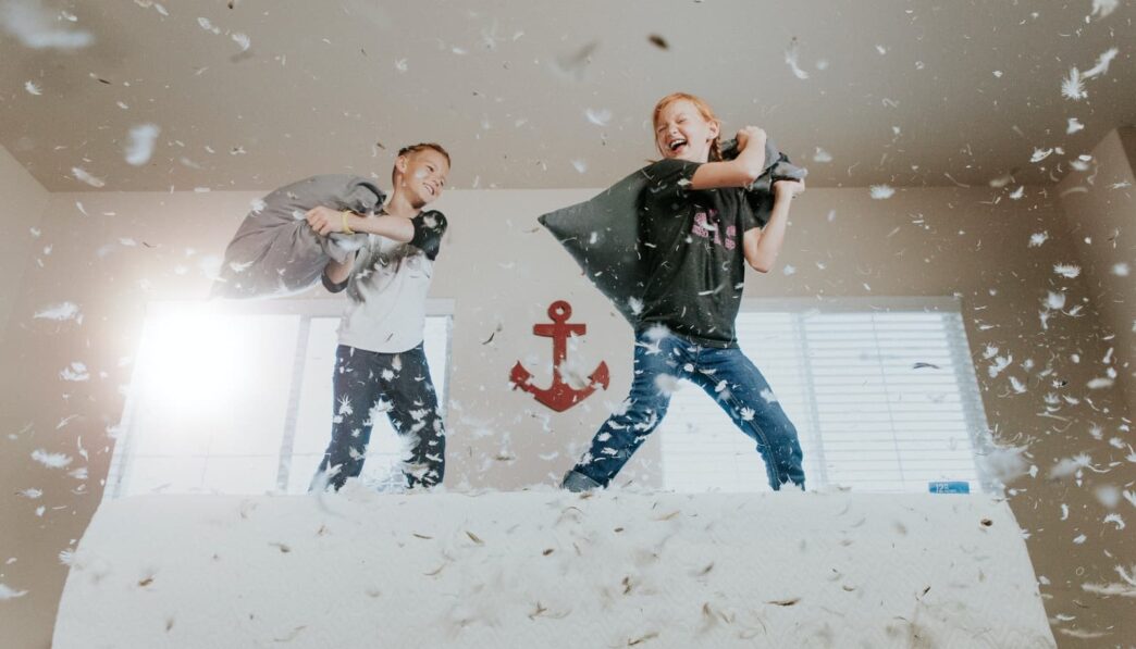 two toddler pillow fighting