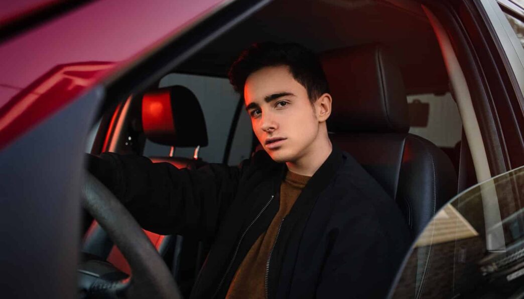man in black suit jacket sitting on car seat
