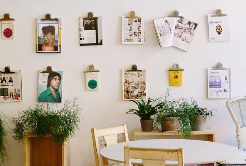 magazines hanged on wall near round beige wooden table