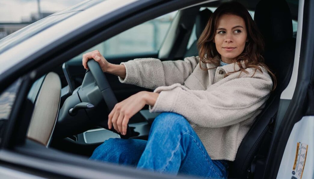 woman in gray sweater and blue denim jeans sitting on car seat