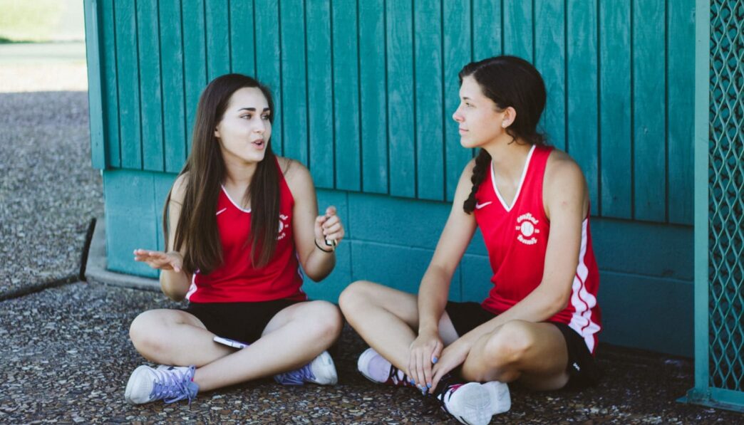woman in red Nike tank top sitting beside woman in red tank top