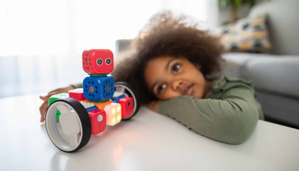 boy lying on bed playing with red and blue toy truck
