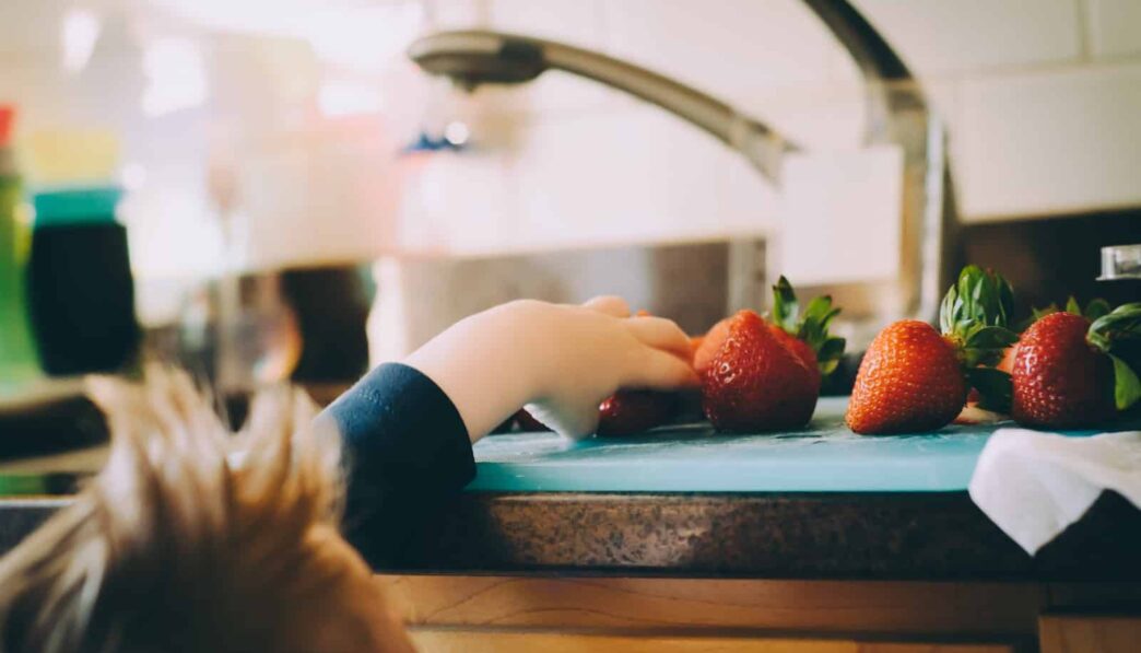child picking strawberries in kitchen