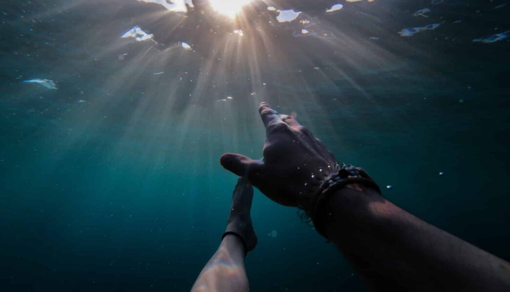underwater photography of person soaking under sun rays