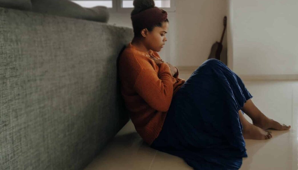man in orange long sleeve shirt sitting on gray couch