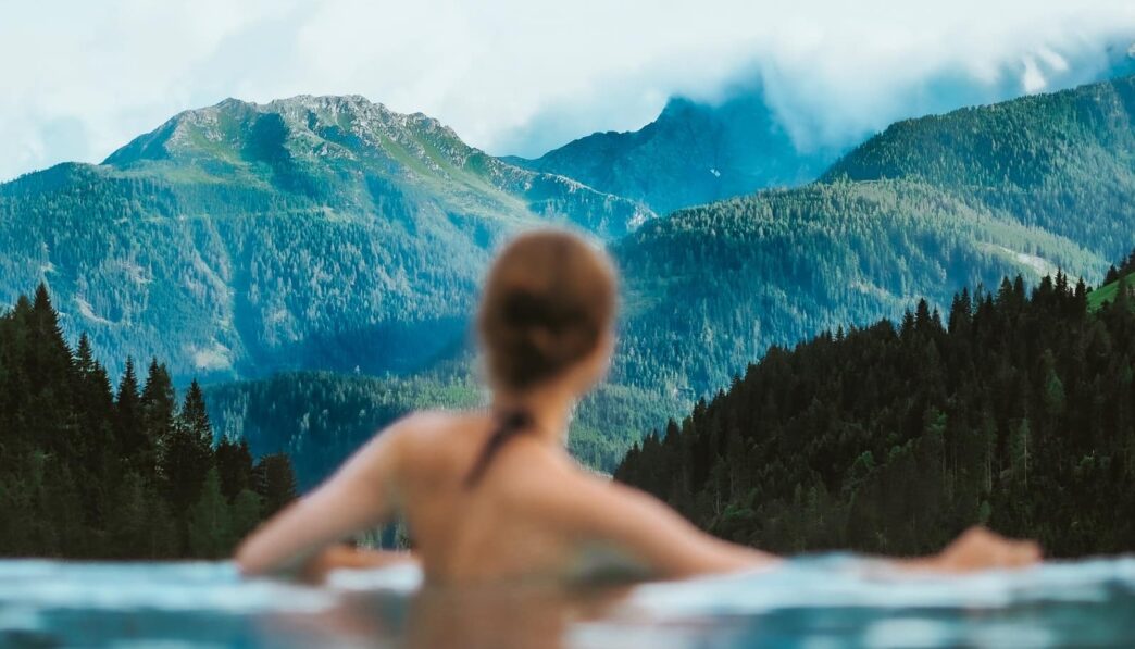 topless boy in water near green trees during daytime