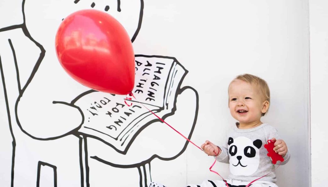smiling toddler holding red balloon