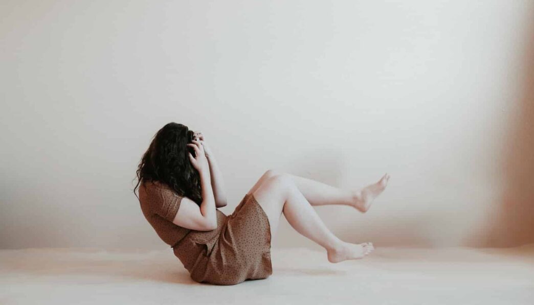 woman sitting on floor wearing brown dress