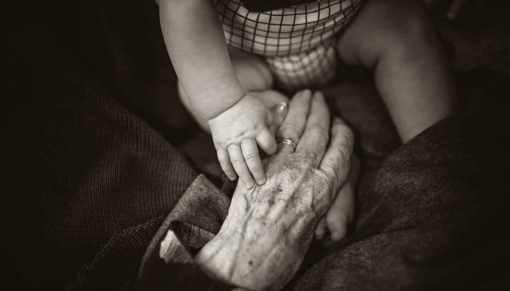 an older woman holding a baby's hand