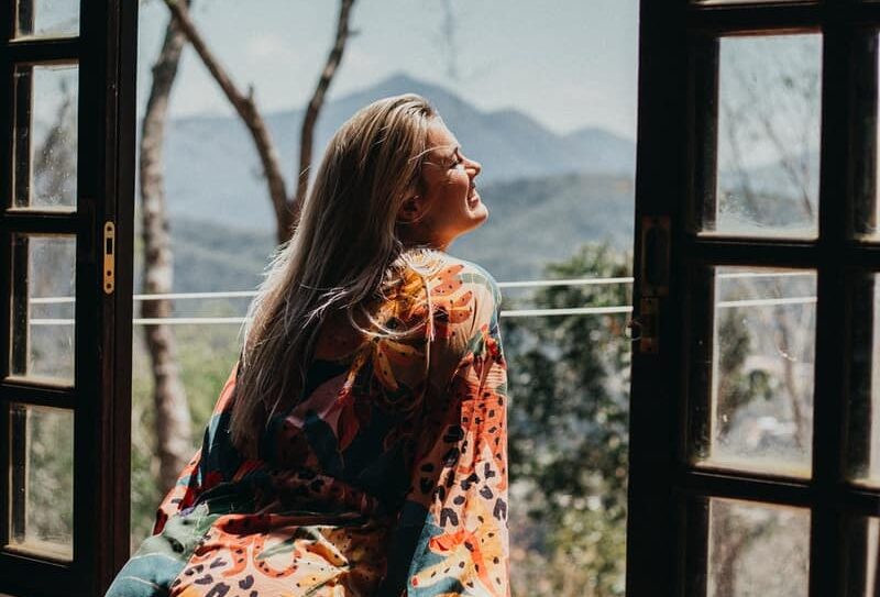 woman in red and white floral long sleeve shirt sitting on brown wooden chair