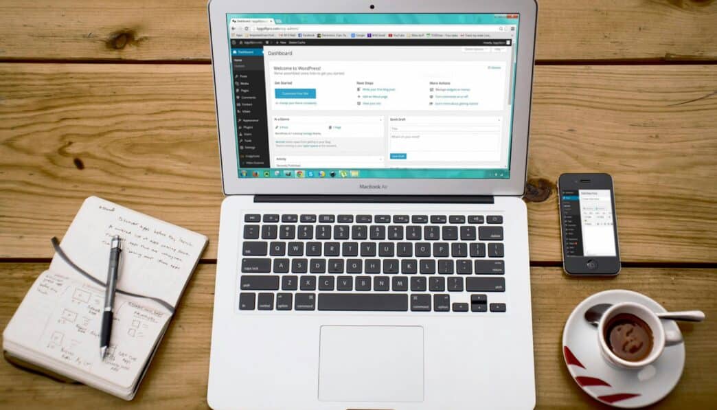 A cozy home office scene with a laptop, notebook, smartphone, and coffee, perfect for productivity.