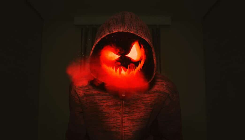 A spooky pumpkin head in a hoodie exudes a creepy Halloween vibe with red smoke.