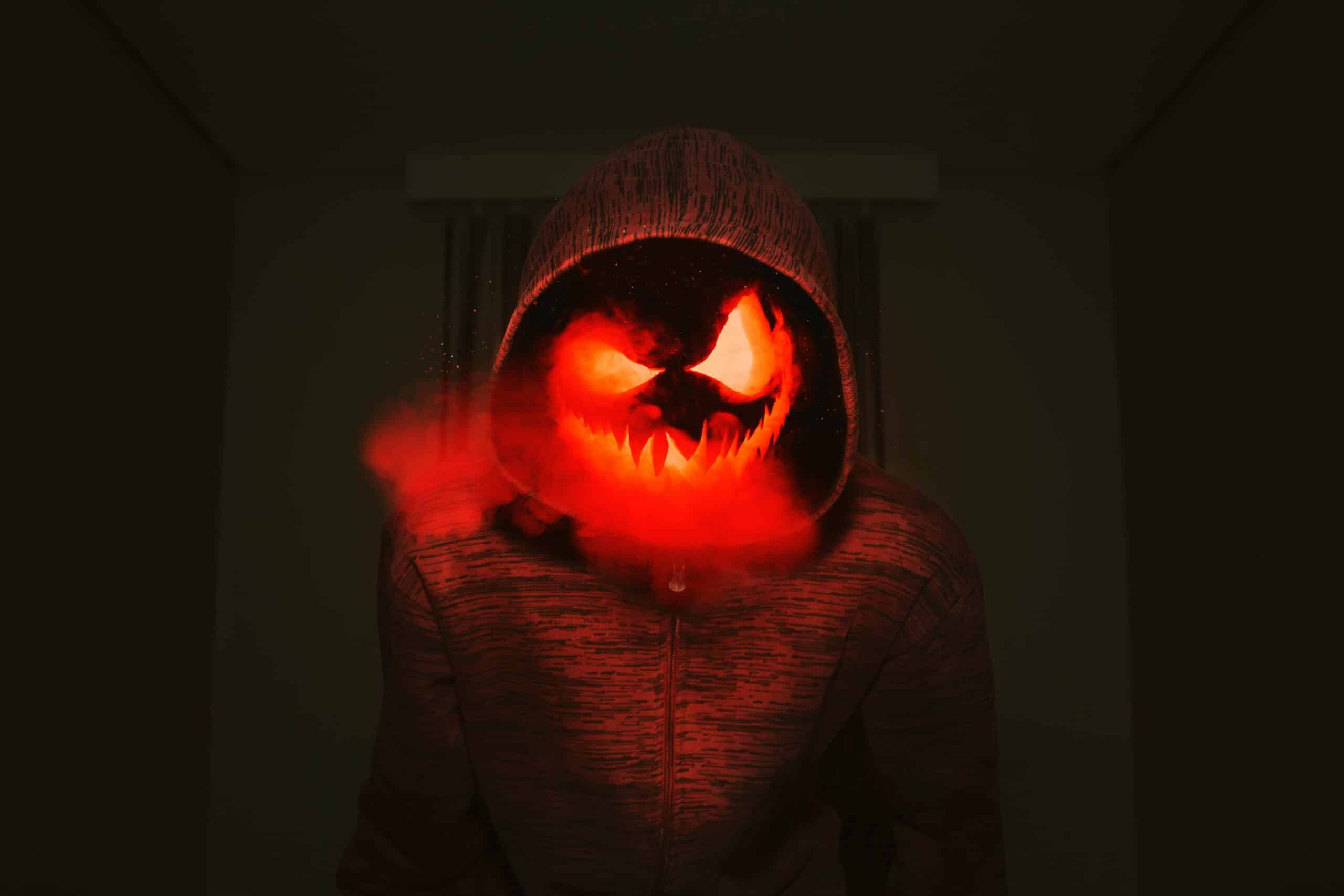 A spooky pumpkin head in a hoodie exudes a creepy Halloween vibe with red smoke.