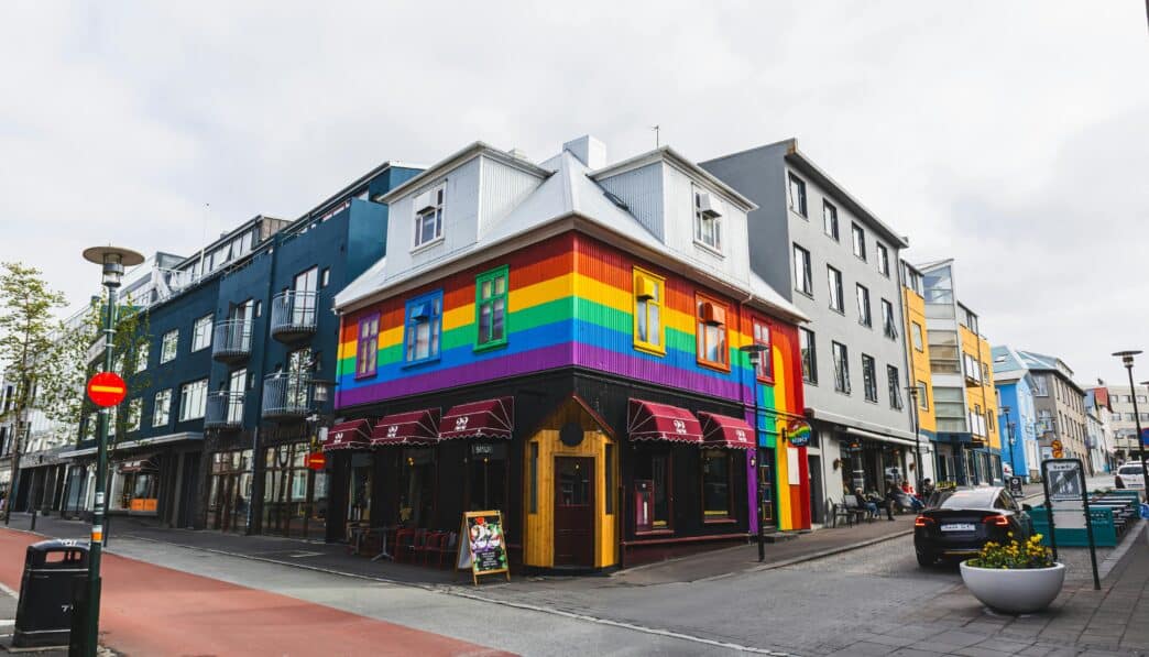 Vibrant rainbow building on a Reykjavík street corner, showcasing LGBTQ inclusivity.