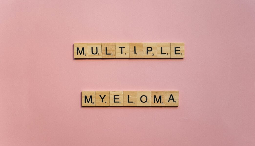 Wooden letter tiles spelling 'Multiple Myeloma' on a pink background.