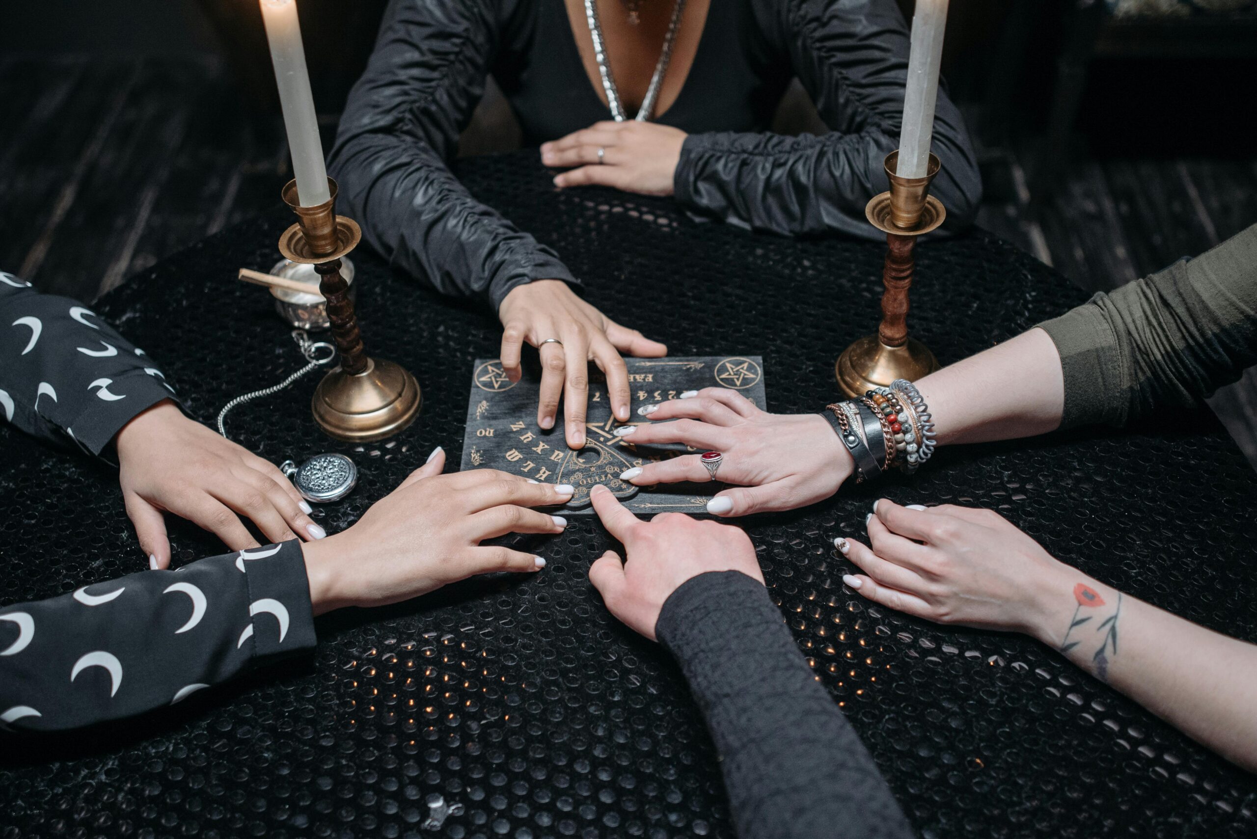 A group gathered around a Ouija board, exploring spirituality and the occult in a dimly lit room.